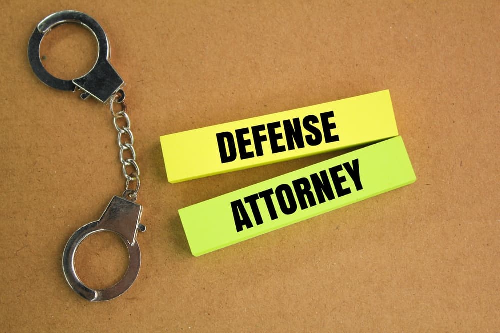 Metal handcuffs alongside a colorful sheet of paper labeled "Defense Attorney."