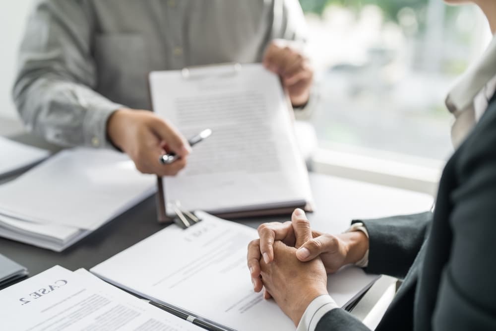 Lawyer presenting a signed contract to a client, with a gavel and legal scales in the background, symbolizing justice, legal counsel, and business partnership.