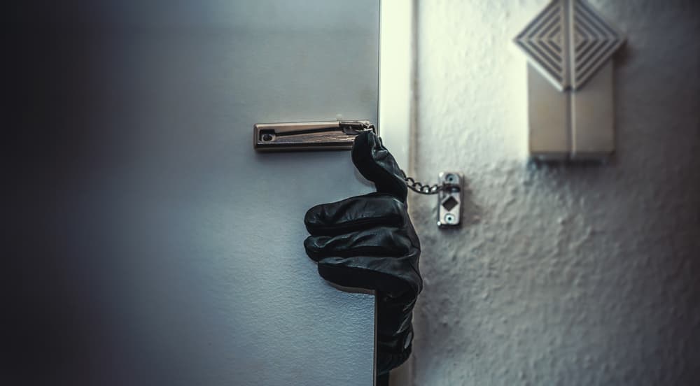 Masked burglar with crowbar breaking and entering into a victim's home