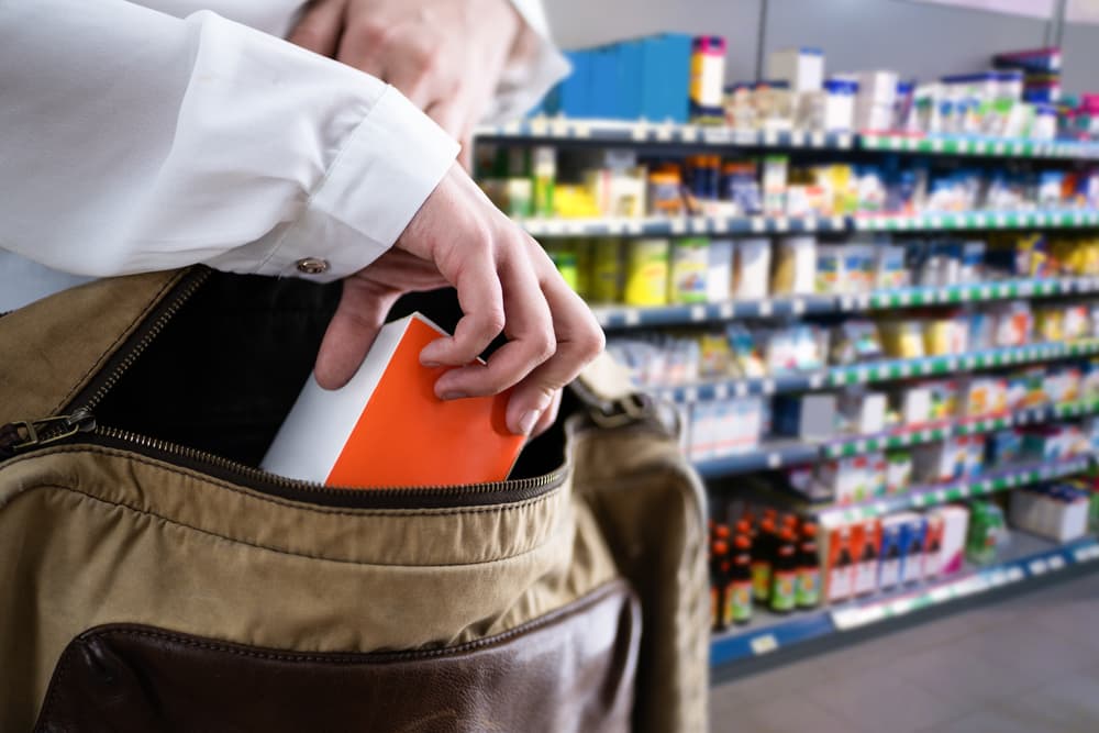 Retail theft incident: a woman caught stealing items in a supermarket, showcasing the act of shoplifting in a retail environment.