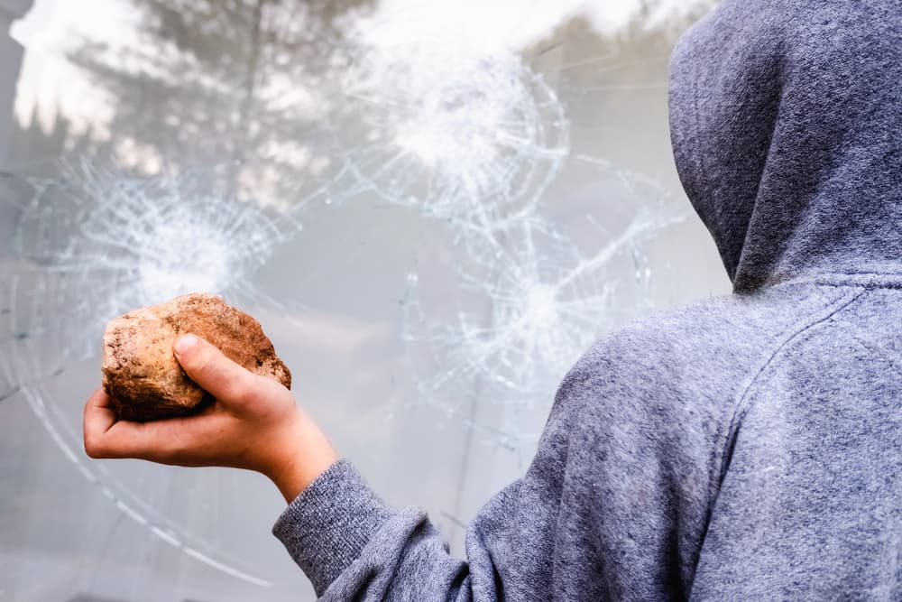 A protester raising a rock to smash a shop window in the street during a demonstration.
