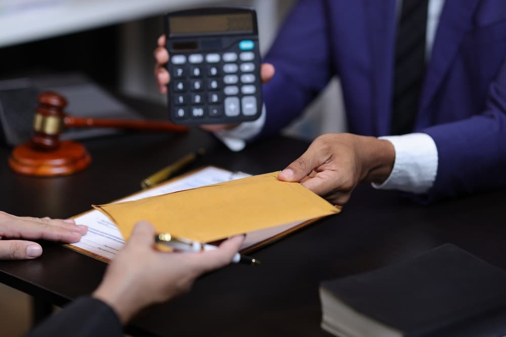 Lawyers discussing legal fees using calculator in law office.