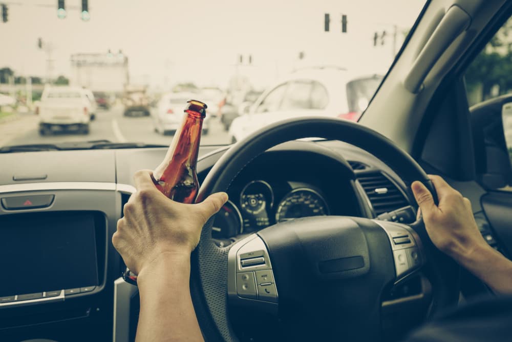 A driver holding alcoholic bottle while driving / Drunk driving