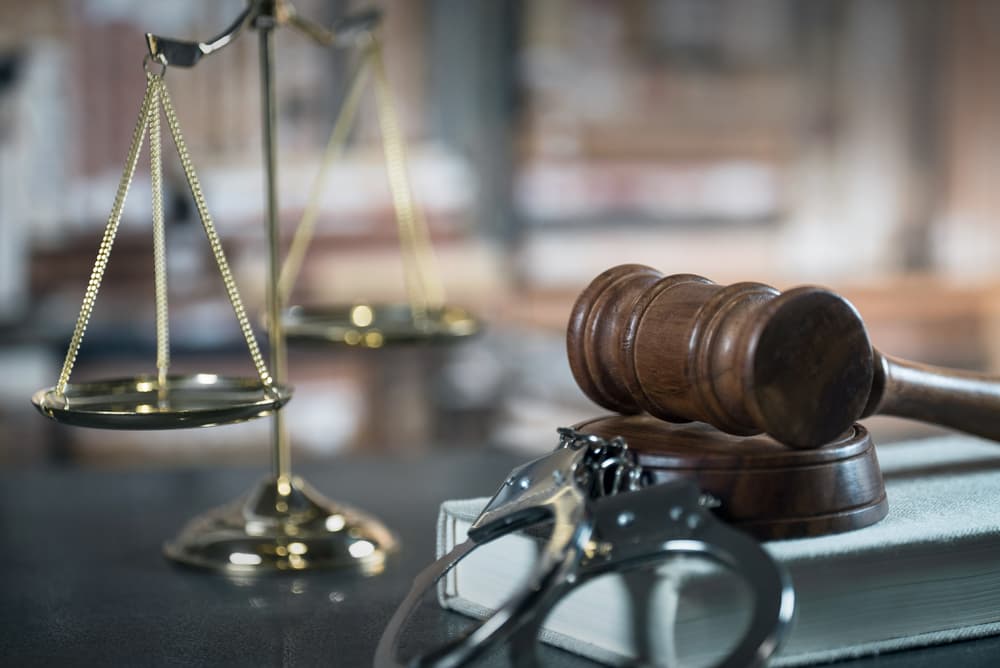 Handcuffs and gavel on dark rustic table at Criminal Defense Lawyer office