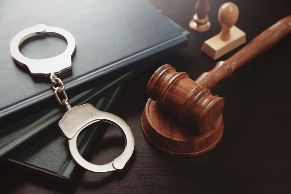 Arrest concept. Metal handcuffs near judge gavel.